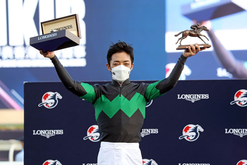 Winning jockey Loves Only You poses for a photo with a bronze horse and jockey statuette and a LONGINES Master Collection watch.