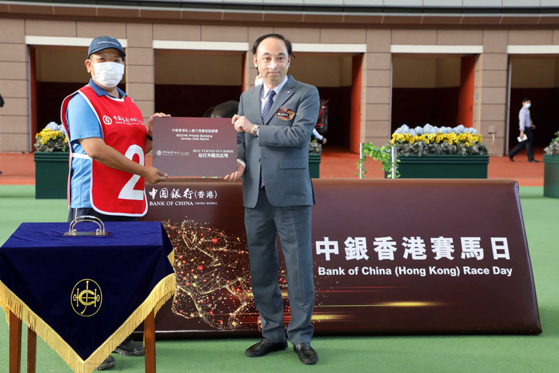 Before the race, Mr. Lam Yan Chuen, Deputy General Manager, Private Banking of Bank of China (Hong Kong) Limited, presents a prize at the parade ring to the stable assistant responsible for Wellington, the best turned out horse in the BOCHK Private Banking Jockey Club Sprint.