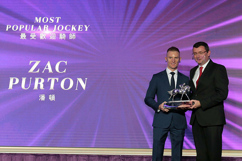 Zac Purton receives the Most Popular Jockey of the Year trophy from Mr Andrew Weir, Steward of The Hong Kong Jockey Club.