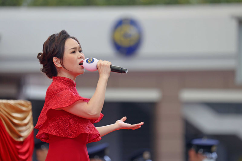 Ms Phoebe Tam Lok Hin, Hong Kong Soprano, leads the singing of the National Anthem, accompanied by the Hong Kong Police Band.