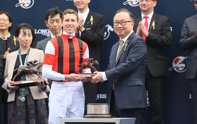 馬會董事廖長江先生頒發浪琴香港瓶獎盃及騎師駿馬銅像予「瑪蓮必勝」的馬主代表、練馬師手塚貴久及騎師連達文。