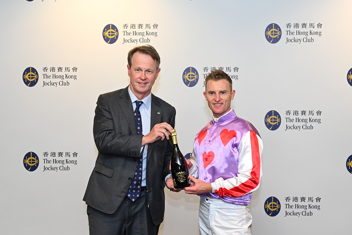 Zac Purton receives a commemorative bottle of champagne from Andrew Harding, Executive Director, Racing, The Hong Kong Jockey Club.