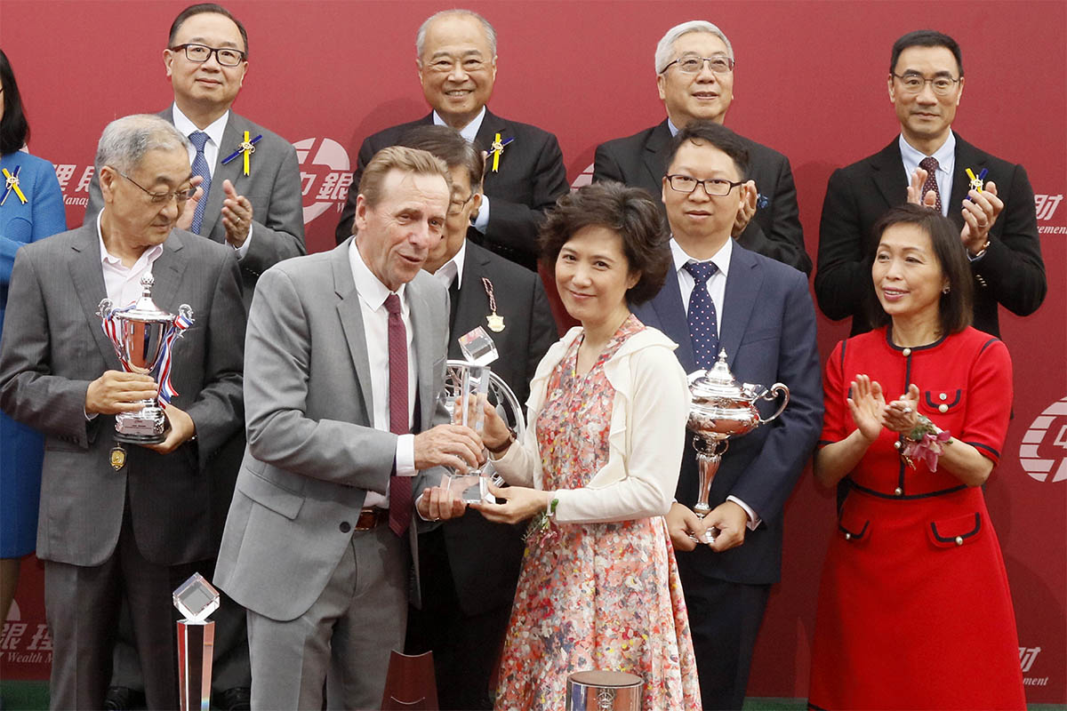 中國銀行（香港）有限公司私人銀行總經理曾錦燕（右）頒發水晶獎座予「紅衣醒神」的練馬師蔡約翰。
