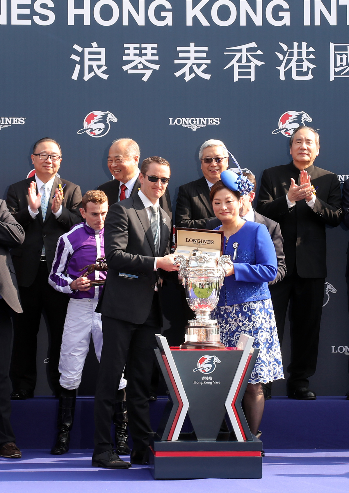 LONGINES香港區副總裁歐陽楚英（右）致送紀念品予浪琴表香港瓶冠軍「高地之舞」的馬主代表、練馬師岳伯仁及騎師莫雅。