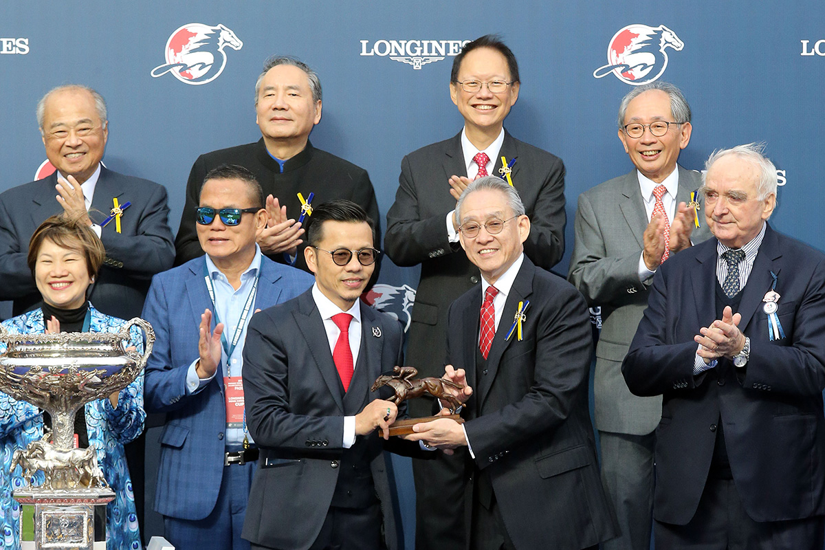 馬會主席周永健先生（右）頒發浪琴表香港盃獎盃予「歡樂之光」的馬主關永樂，以及騎師駿馬銅像予馬主代表、練馬師羅富全與騎師蘇兆輝。