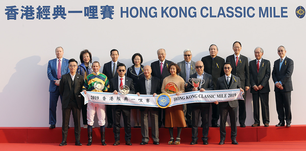馬會主席周永健博士、眾馬會董事、行政總裁應家柏、與「添滿意」的馬主及騎練，於香港經典一哩賽頒獎禮上合照。