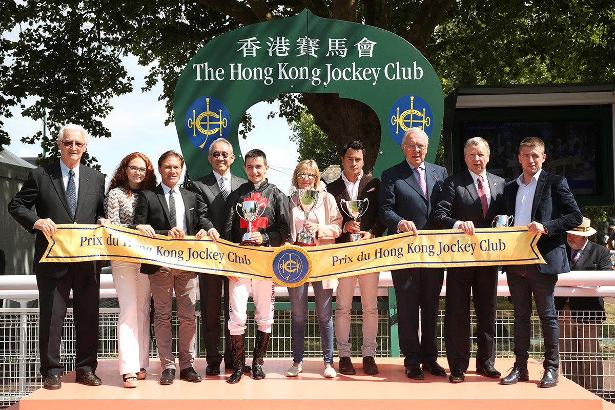香港賽馬會主席周永健博士（左四）在法國賽馬會副主席Jean-Pierre Colombu（右三）、國際賽馬組織聯盟主席Louis Romanet（左一）及香港賽馬會行政總裁應家柏（右二）陪同下，頒發獎盃予香港賽馬會錦標冠軍Queen Morny的幕後團隊。