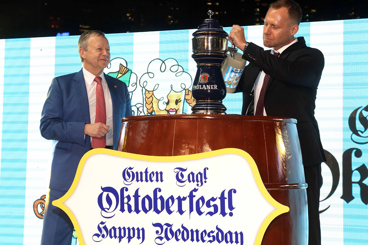 德國駐港副總領事Mr. David Schmidt（右）斟滿首杯啤酒宣告節慶開始，隨後並與香港賽馬會行政總裁應家柏先生（左）以及現場人士一同舉杯慶祝啤酒節揭幕。