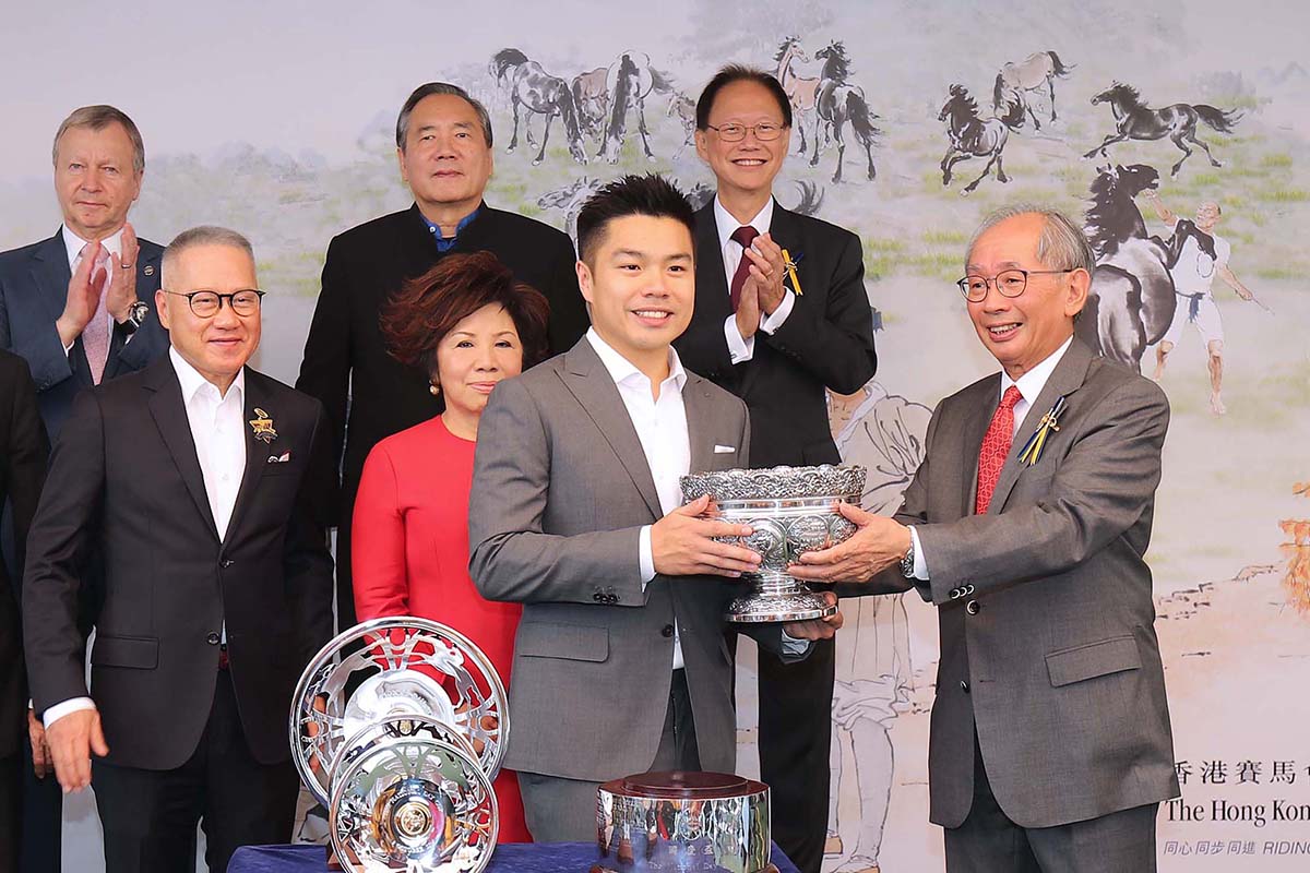 馬會副主席郭志桁先生（右），將國慶盃的獎盃頒發予勝出馬匹「美麗滿載」的馬主美麗一族團體代表。