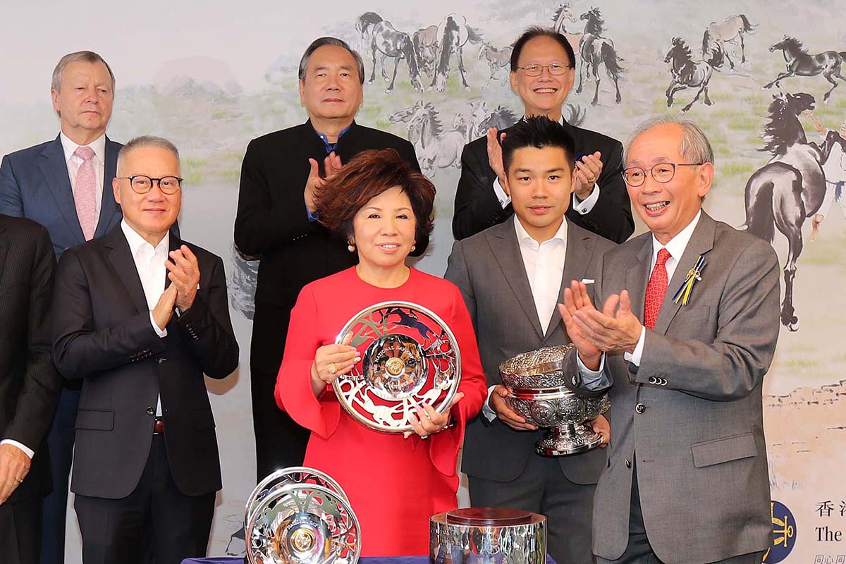 馬會副主席郭志桁先生（右），將國慶盃的獎盃頒發予勝出馬匹「美麗滿載」的馬主美麗一族團體代表。