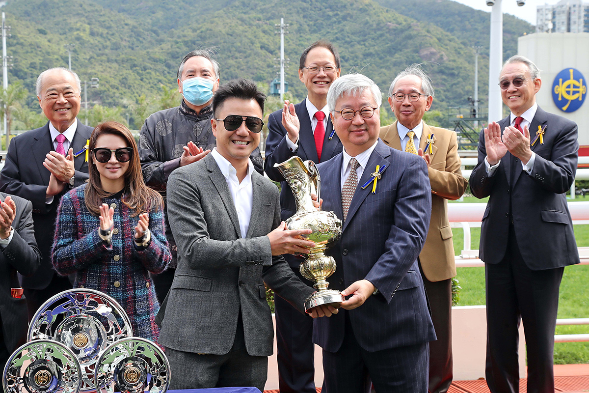 馬會董事楊紹楊紹信（右）頒發百週年紀念銀瓶獎盃及銀碟予「時時精綵」的馬主代表、練馬師告東尼及騎師潘頓。