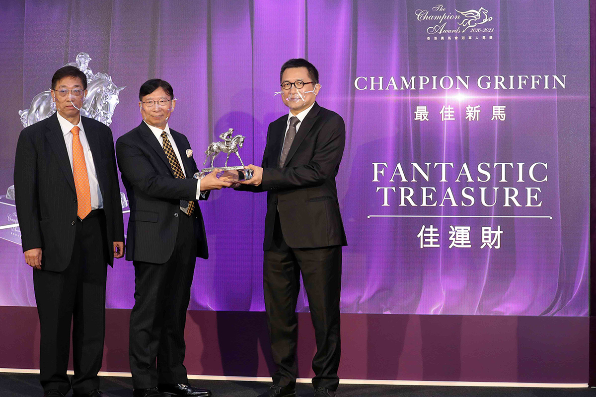 香港評馬同業協進會主席吳伽樂先生頒發最佳新馬獎座予「佳運財」的馬主梁煥乾先生與梁坤先生。