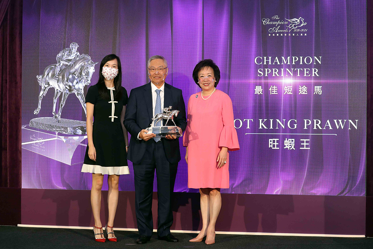香港賽馬會董事王䓪鳴博士頒發最佳短途馬獎座予「旺蝦王」的馬主劉錫康先生及馬主的女兒劉津津。