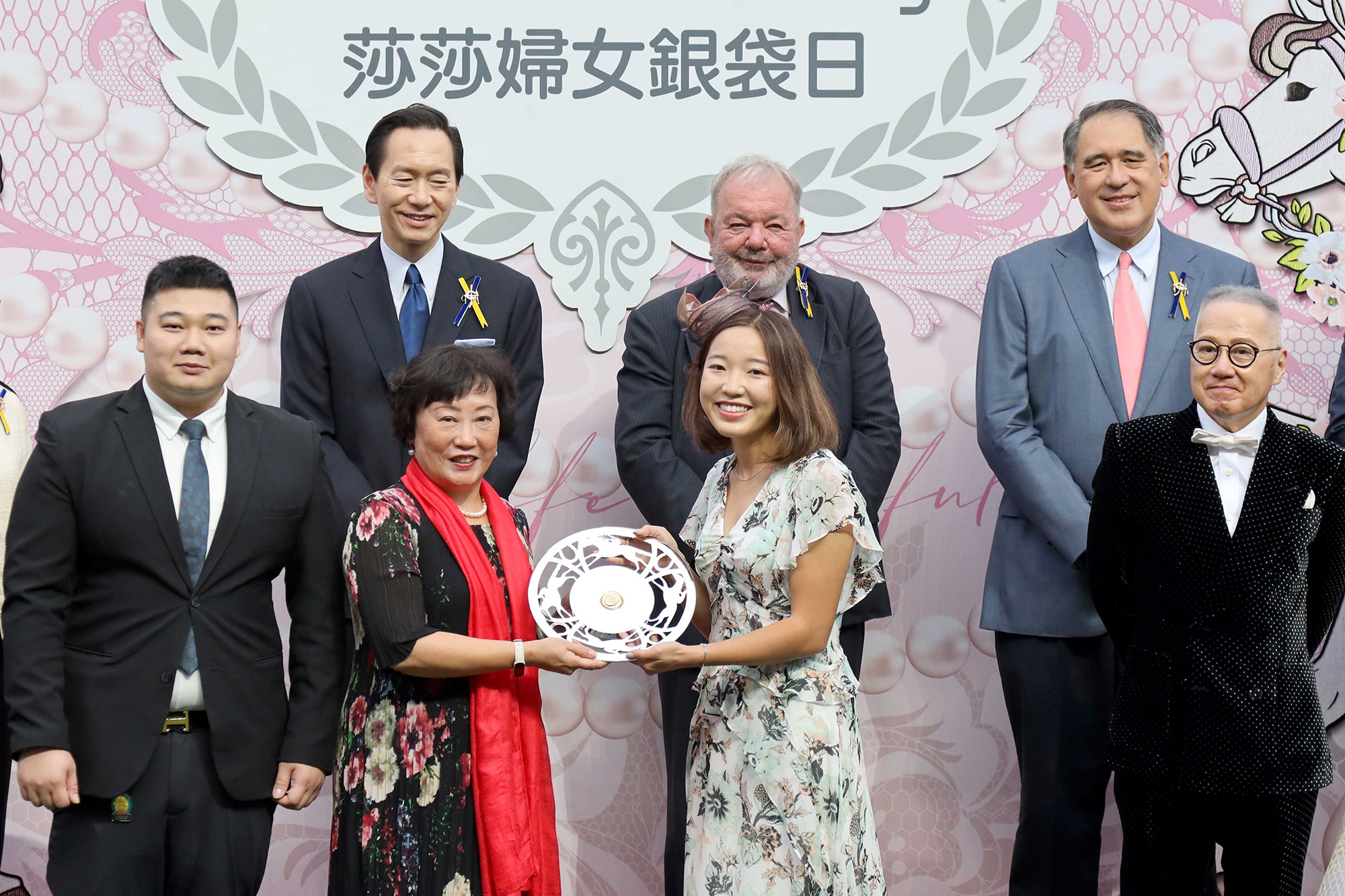 香港賽馬會遴選會員兼馬主何志強先生的女兒何妍臻小姐，在莎莎婦女銀袋頒獎儀式上頒發紀念銀碟予得勝馬匹「發財先鋒」的馬主太陽花團體代表。