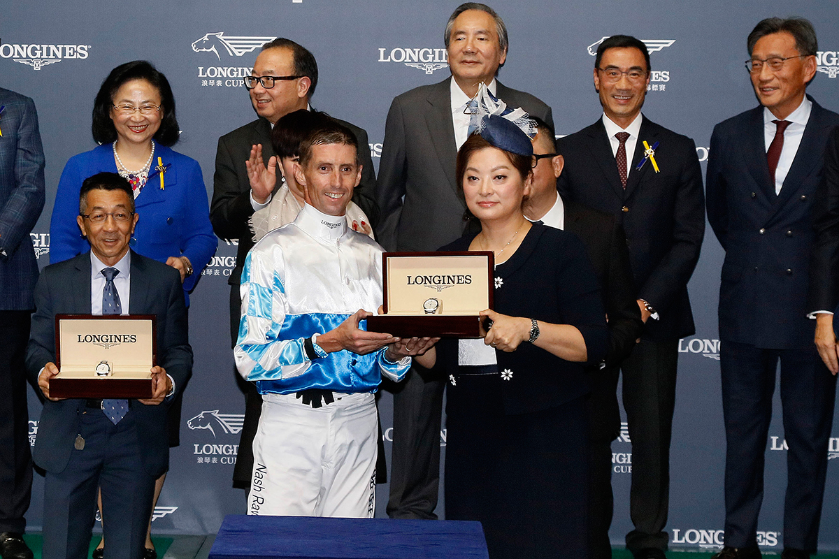 Ms. Karen Au Yeung, Vice President of LONGINES Hong Kong, presents a LONGINES Conquest Classic Collection watch to jockey Nash Rawiller, winning connections of Look Eras.