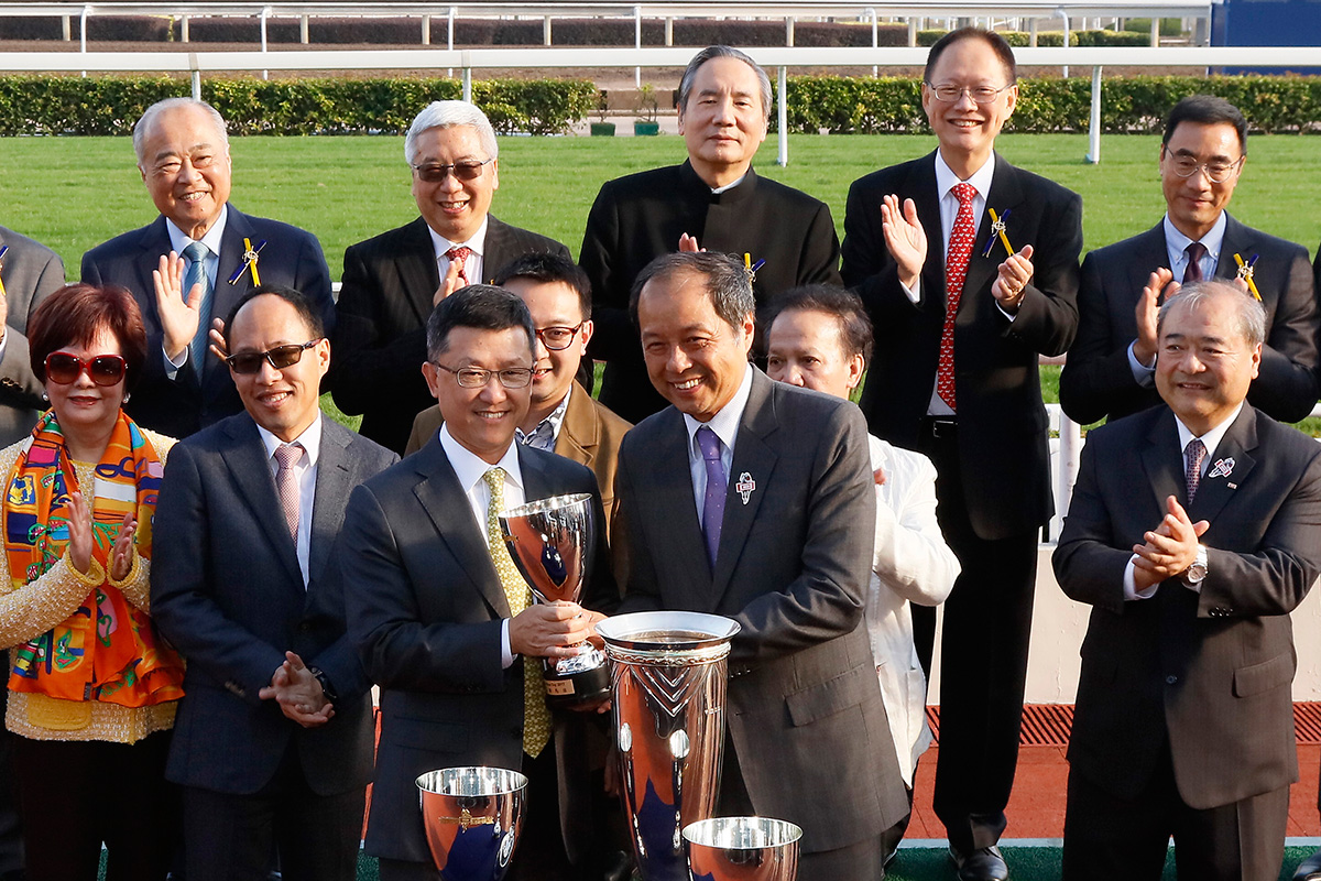 Mr. Tam Kwok Wing, Deputy Managing Director of Chevalier International Holdings Limited, presents a replica trophy to winning trainer Peter Ho.