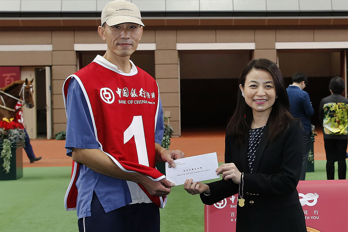Before the race, Ms Mary Lo Wai Man (right), Deputy General Manager, Personal Banking and Wealth Management Department of the Bank of China (Hong Kong) Limited, presents a HK$2,000 prize to the Stables Assistant responsible for Werther, the best turned out horse in the BOCHK Jockey Club Cup.