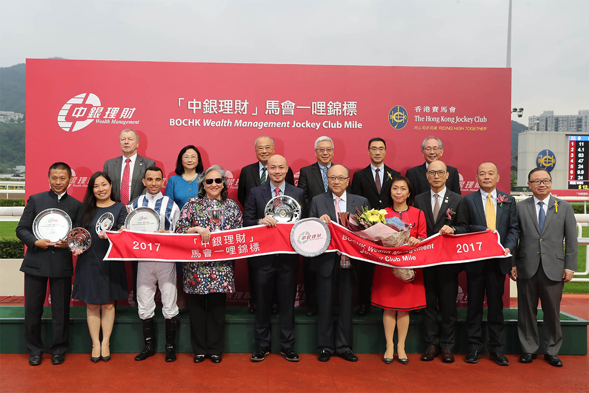 HKJC Stewards, Chief Executive Officer and presenting guests for the BOCHK Wealth Management Jockey Club Mile pose for a group photo with the winning connections of Seasons Bloom.