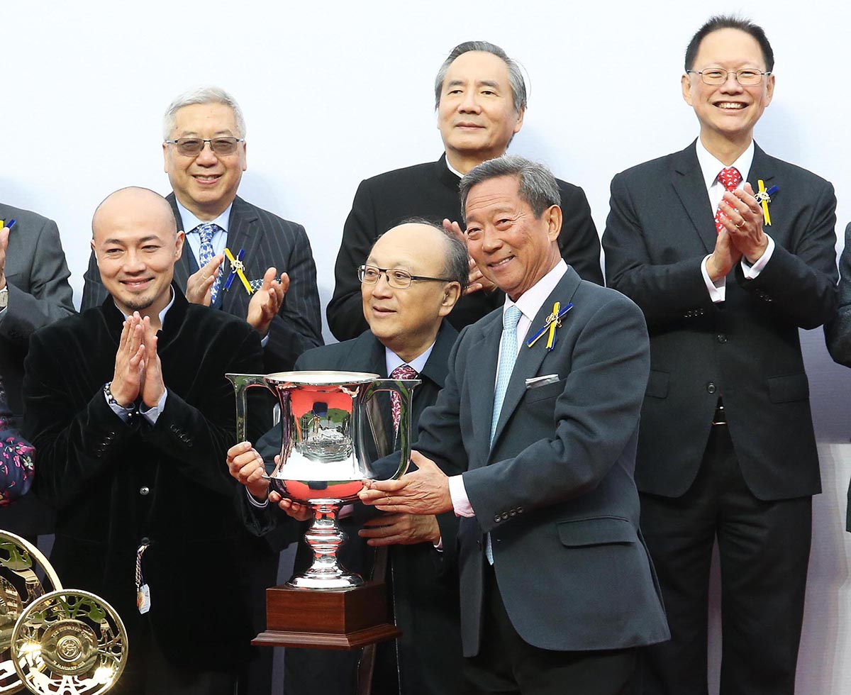 At the presentation ceremony, Club Chairman Dr Simon Ip (right) presents the Stewards’ Cup trophy and gold-plated dishes to Paul Lo Chung Wai, owner of Seasons Bloom, as well as winning trainer Danny Shum and jockey Joao Moreira.