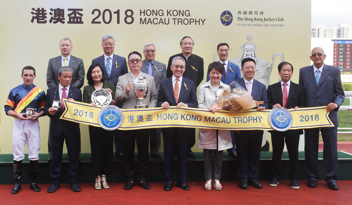 HKJC’s Deputy Chairman Anthony W K Chow (center), Stewards and HKJC’s CEO Winfried Engelbrecht-Bresges (back row, 1st from left); Angela Leong, Vice Chairman and Executive Director of the Macau Jockey Club (front row, 4th from right); senior executives of the MJC; and the connections of Hong Kong Macau Trophy winner California Whip, pose for a group photo at the trophy presentation ceremony.