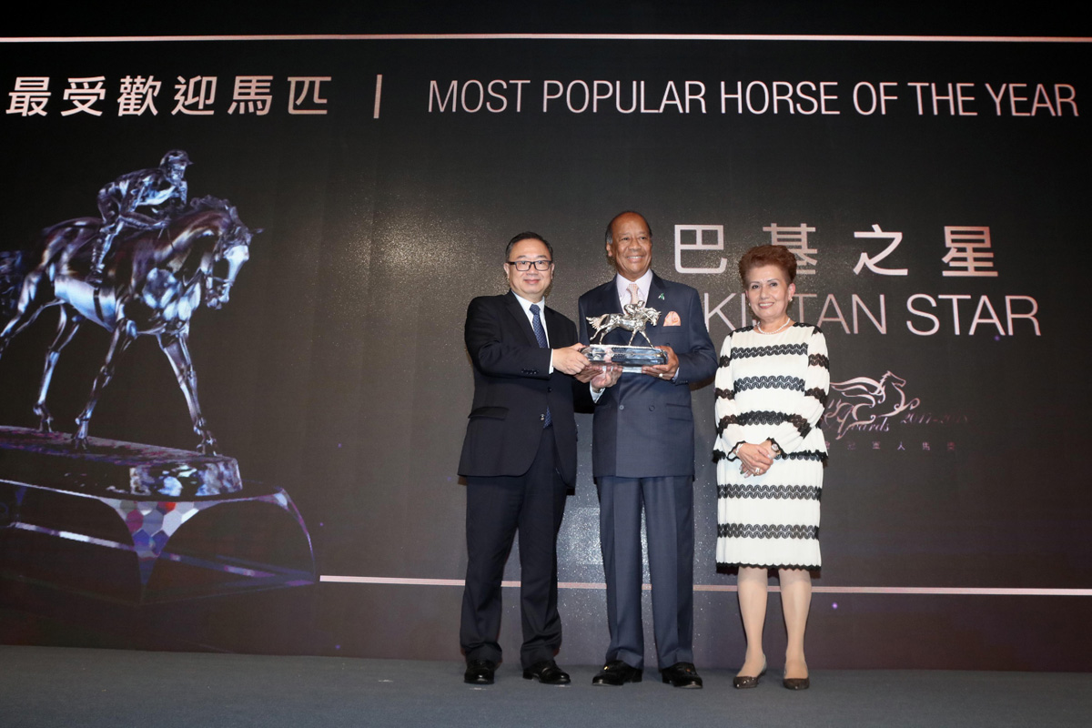 The Hon. Martin Liao, Steward of HKJC, presents the Most Popular Horse of the Year trophy to Mr. Kerm Din, owner of Pakistan Star, accompanied by his wife.