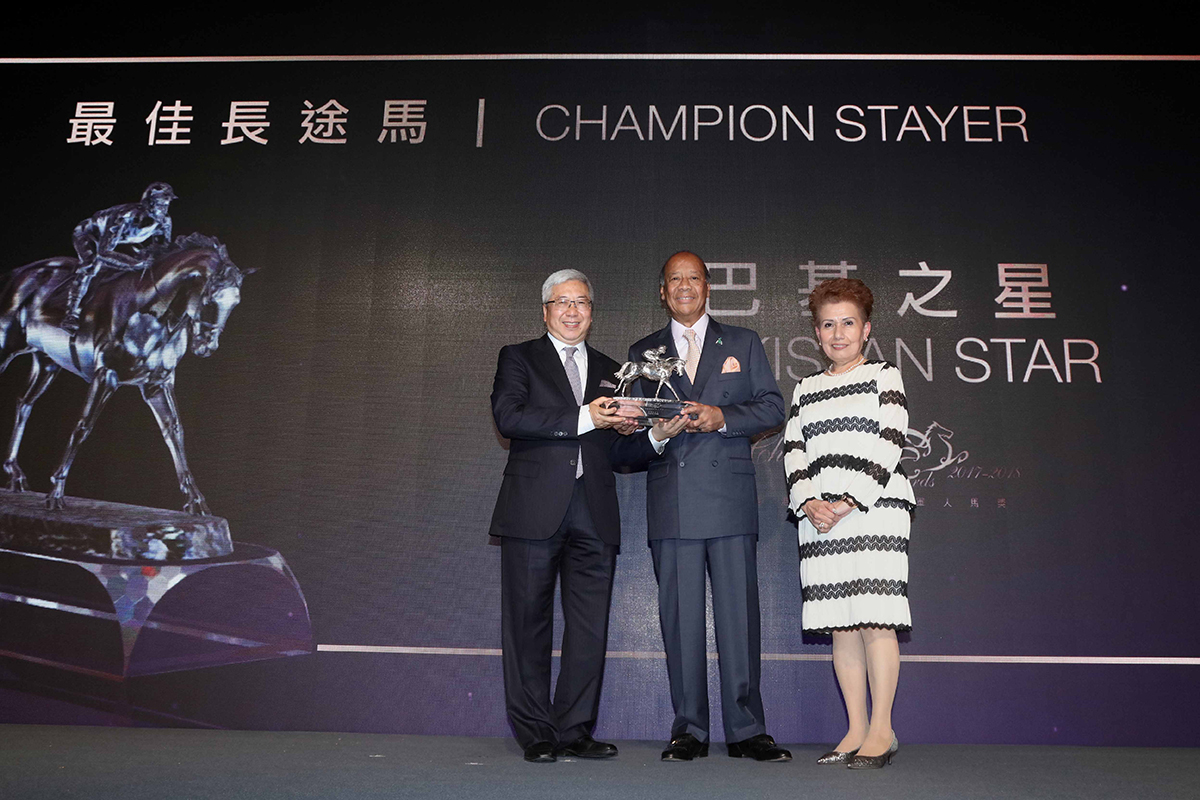 Dr. Eric Li Ka Cheung, Steward of HKJC, presents the Champion Stayer trophy to Mr. Kerm Din, owner of Pakistan Star, accompanied by his wife.