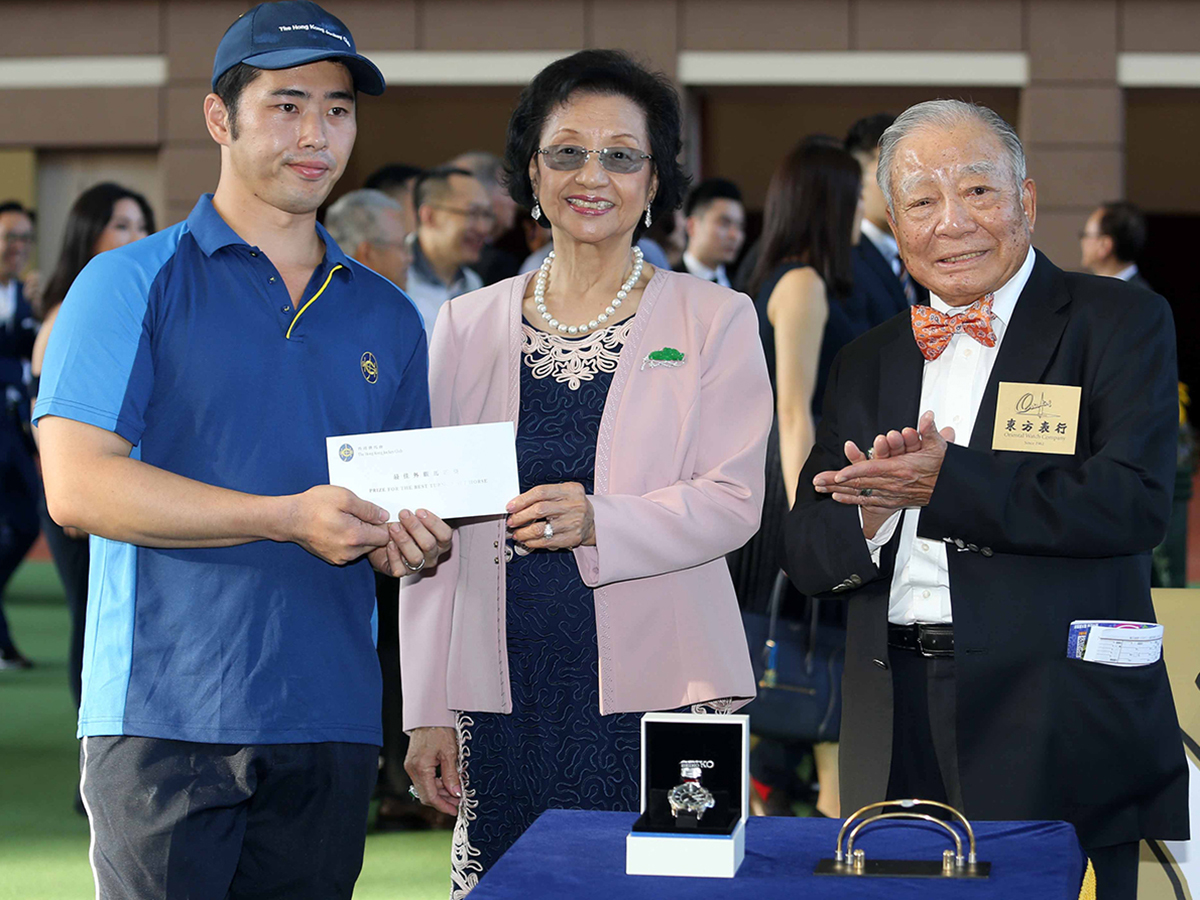 Chairman of the Oriental Watch Holdings Limited Dr. Yeung Ming Biu, accompanied by his wife, presents a prize of HK$2,000 and a watch to the Stables Assistant responsible for Beauty Generation, the Best Turned Out Horse in the Oriental Watch Sha Tin Trophy.