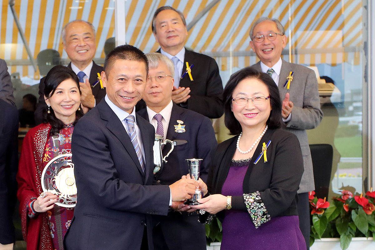 At the trophy presentation ceremony, Club Steward Margaret Leung presents the Griffin Trophy and a silver dish to Mr & Mrs Peter Kung, owner of Perfect Match, trainer Danny Shum and jockey Karis Teetan.
