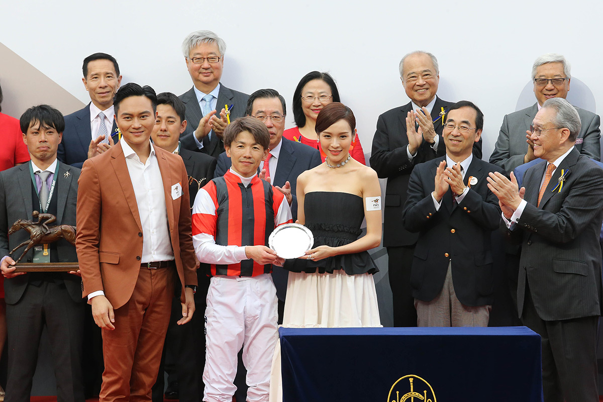 Mr Chi-lam Cheung (left) and Ms Ali Lee, FWD Champions Day Ambassadors, present a souvenir to winning jockey Masami Matsuoka.