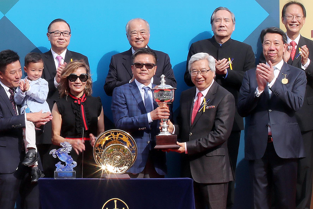 Dr Eric Li Ka Cheung, Steward of the Hong Kong Jockey Club, presents the Standard Chartered Champions & Chater Cup to Eddie Wong Ming Chak and Wong Leung Sau Hing, the Owners of Exultant.