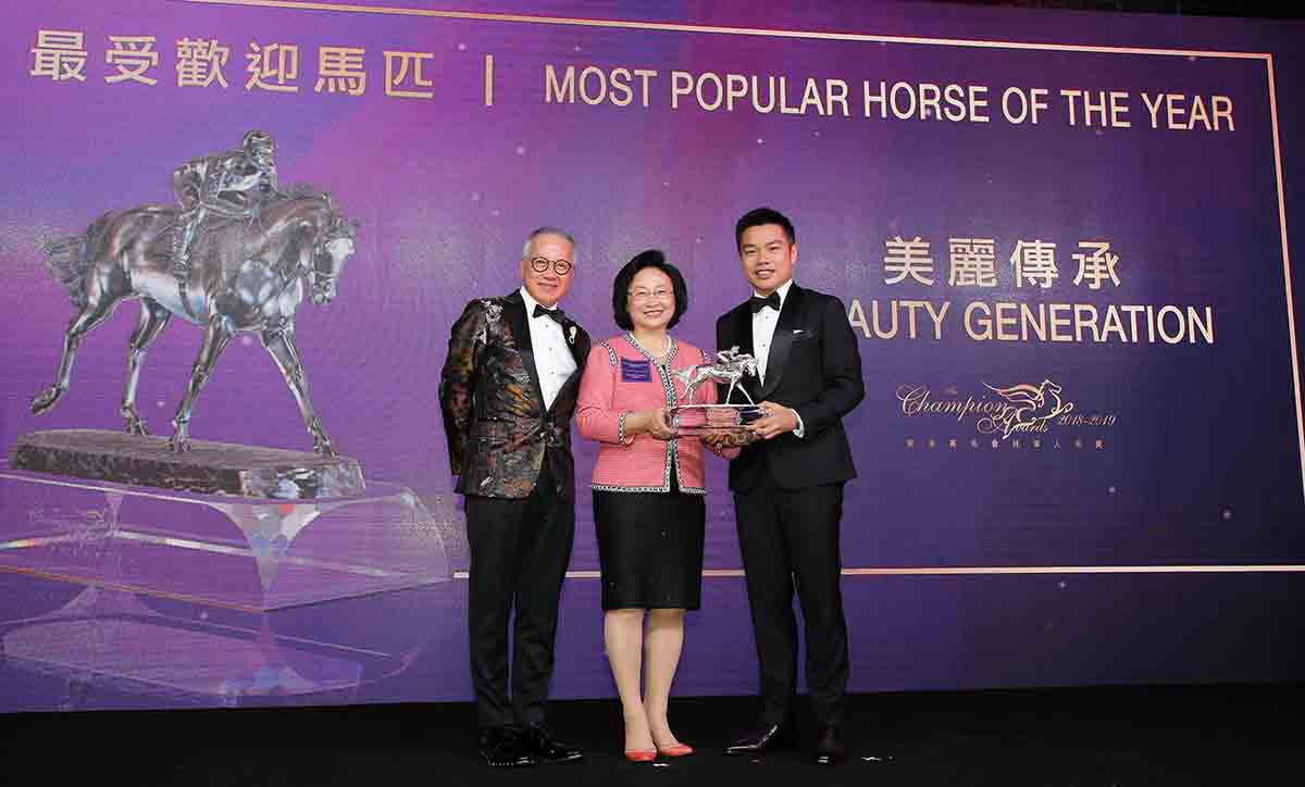 Mrs. Margaret Leung, Steward of The Hong Kong Jockey Club, presents the Most Popular Horse of the Year trophy to Mr. Patrick Kwok Ho Chuen, owner of Beauty Generation, accompanied by his father Dr. Simon Kwok Siu Ming.