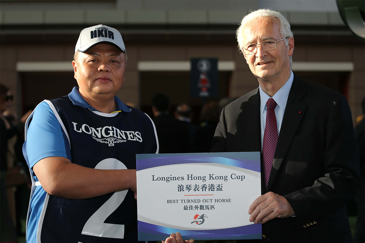 Mr Louis Romanet(right), Chairman of the International Federation of Horseracing Authorities, presents a cheque of HK$5,000 to the groom responsible for Rise High, the Best Turned Out Horse in the LONGINES Hong Kong Cup.