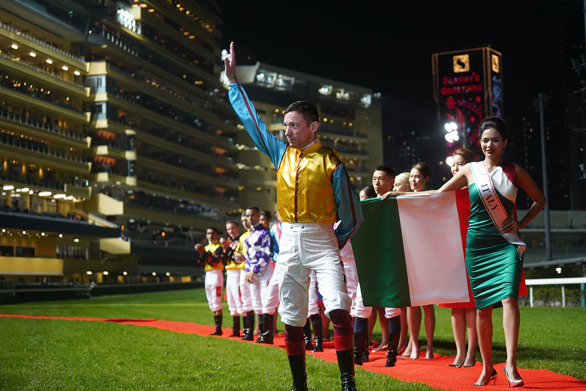 Jockeys enter the turf track in front of the crowd.