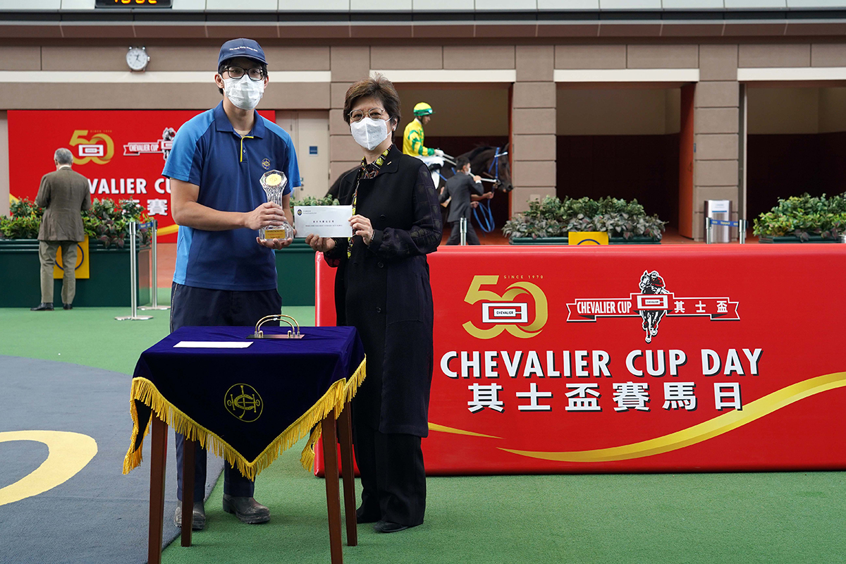 Before the race, Ms Lily Chow, Executive Director of Chevalier International Holdings Limited, presents a prize of HK$1,500, a commemorative crystal stand and a cash coupon of HK$2,000 from the Chevalier Group, to the Stables Assistant responsible for Sky Darci, the Best Turned Out Horse in the Chevalier Cup.