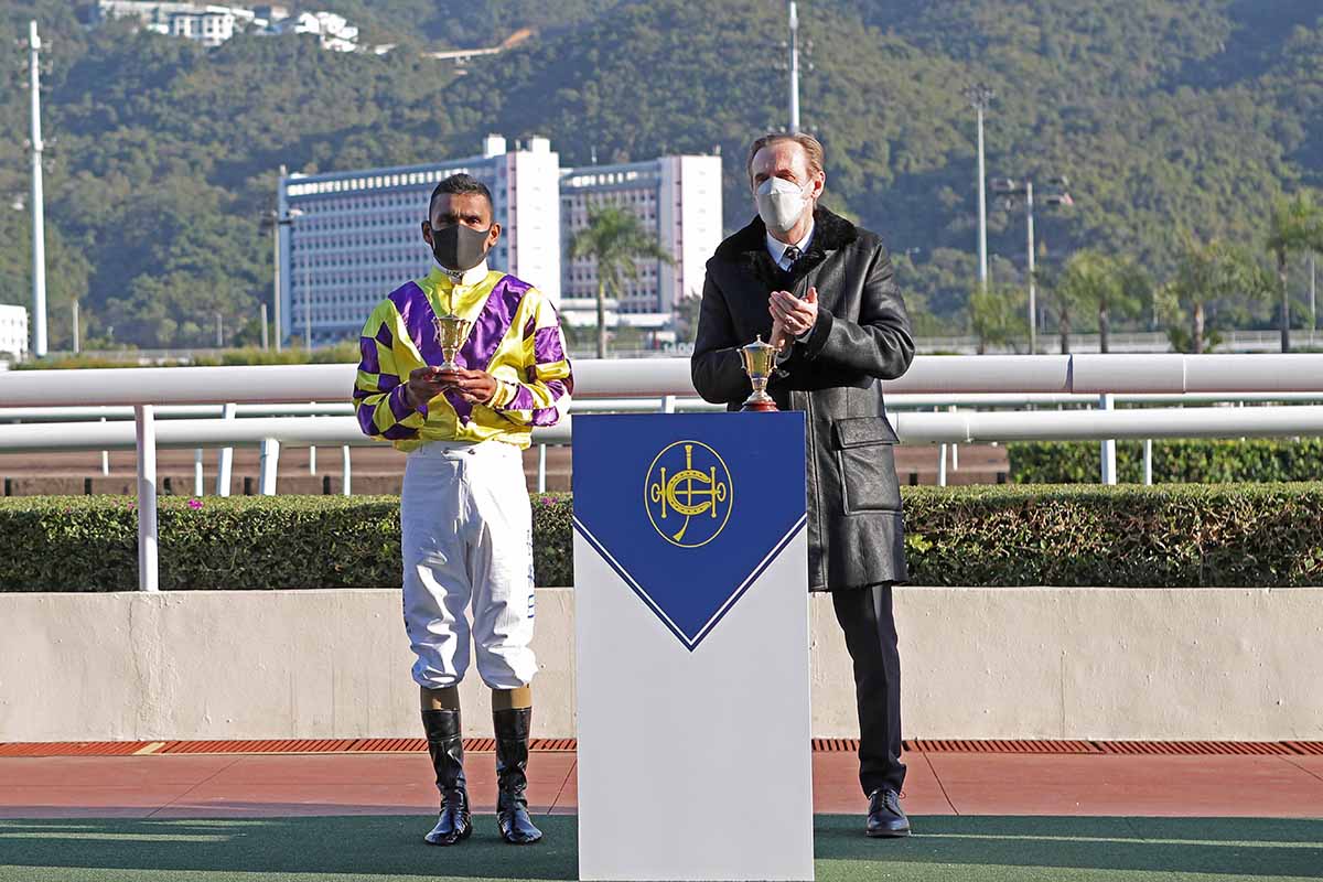 Trainer John Size and jockey Karis Teetan pose for a photo with the trophy miniatures.