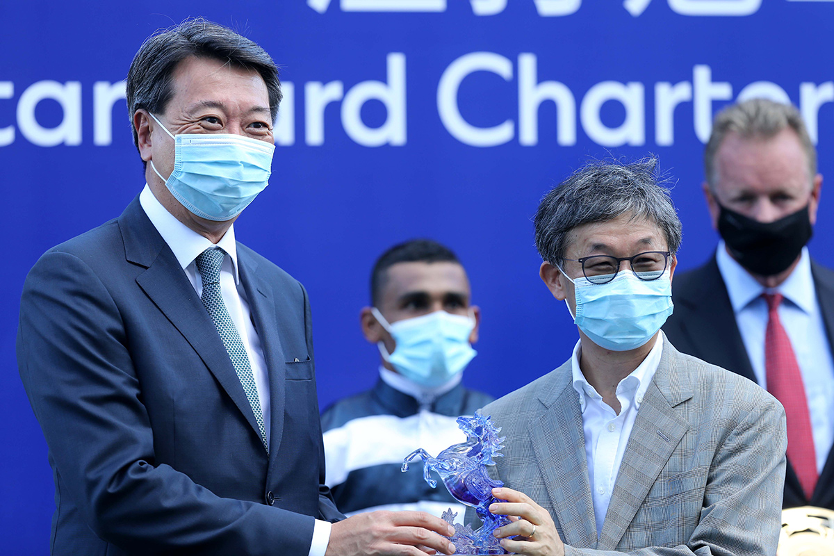 Benjamin Hung (left), Chief Executive Officer, Asia, Standard Chartered Bank, presents souvenirs to Panfield’s Owner representative and jockey Karis Teetan.