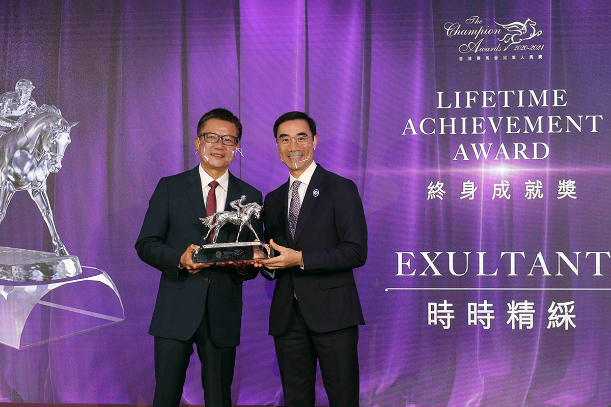 Mr. Michael Lee, Deputy Chairman of The Hong Kong Jockey Club, presents the Lifetime Achievement Award trophy to Mr. Eddie Wong Ming Chak, owner of Exultant.