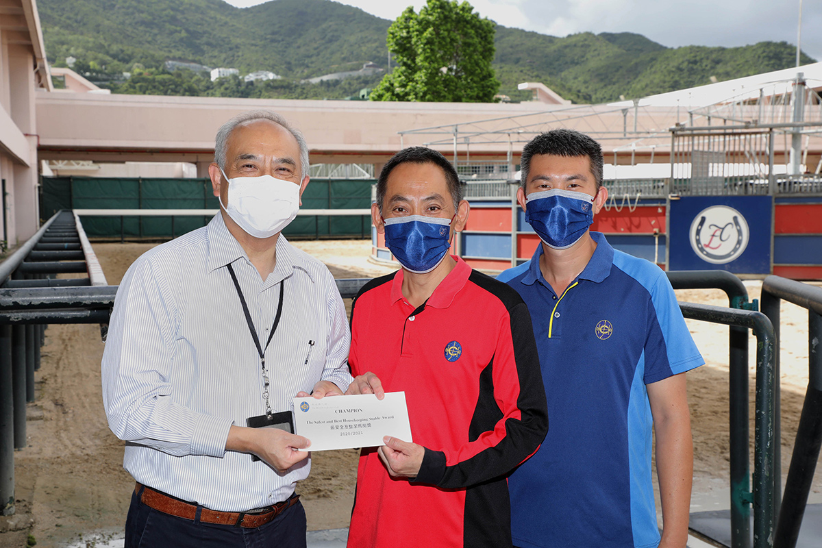Mr. K L Cheng (left), the Club’s Head of Dual Site Stables Operations and Owners Services, presents the stable prize to the representative of the stable staff of Frankie Lor.