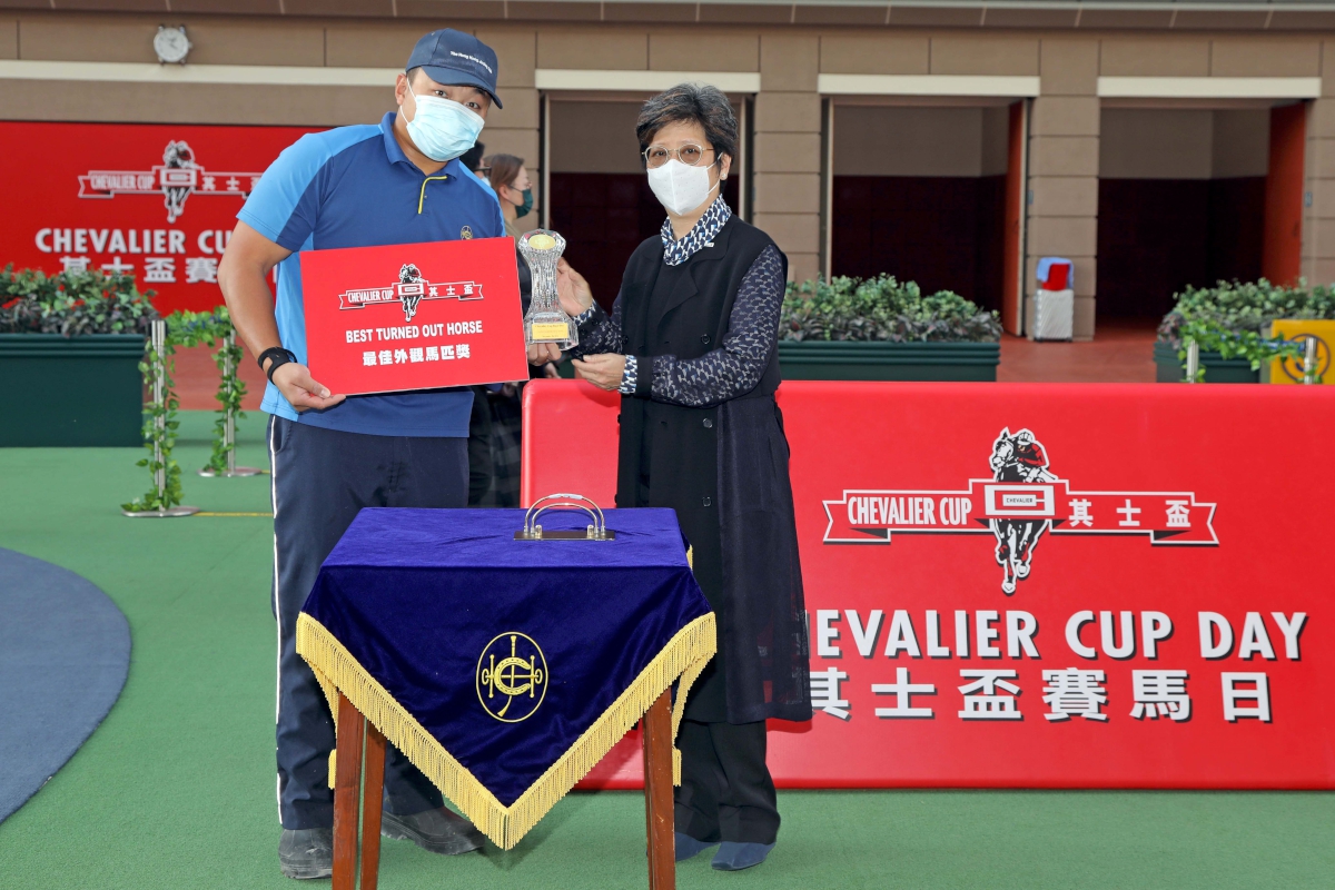 Before the race, Ms Lily Chow, Executive Director of Chevalier International Holdings Limited, presents a prize, a commemorative crystal stand and a cash coupon of HK$2,000 from the Chevalier Group, to the Stables Assistant responsible for The Rock, the Best Turned Out Horse in the Chevalier Cup.